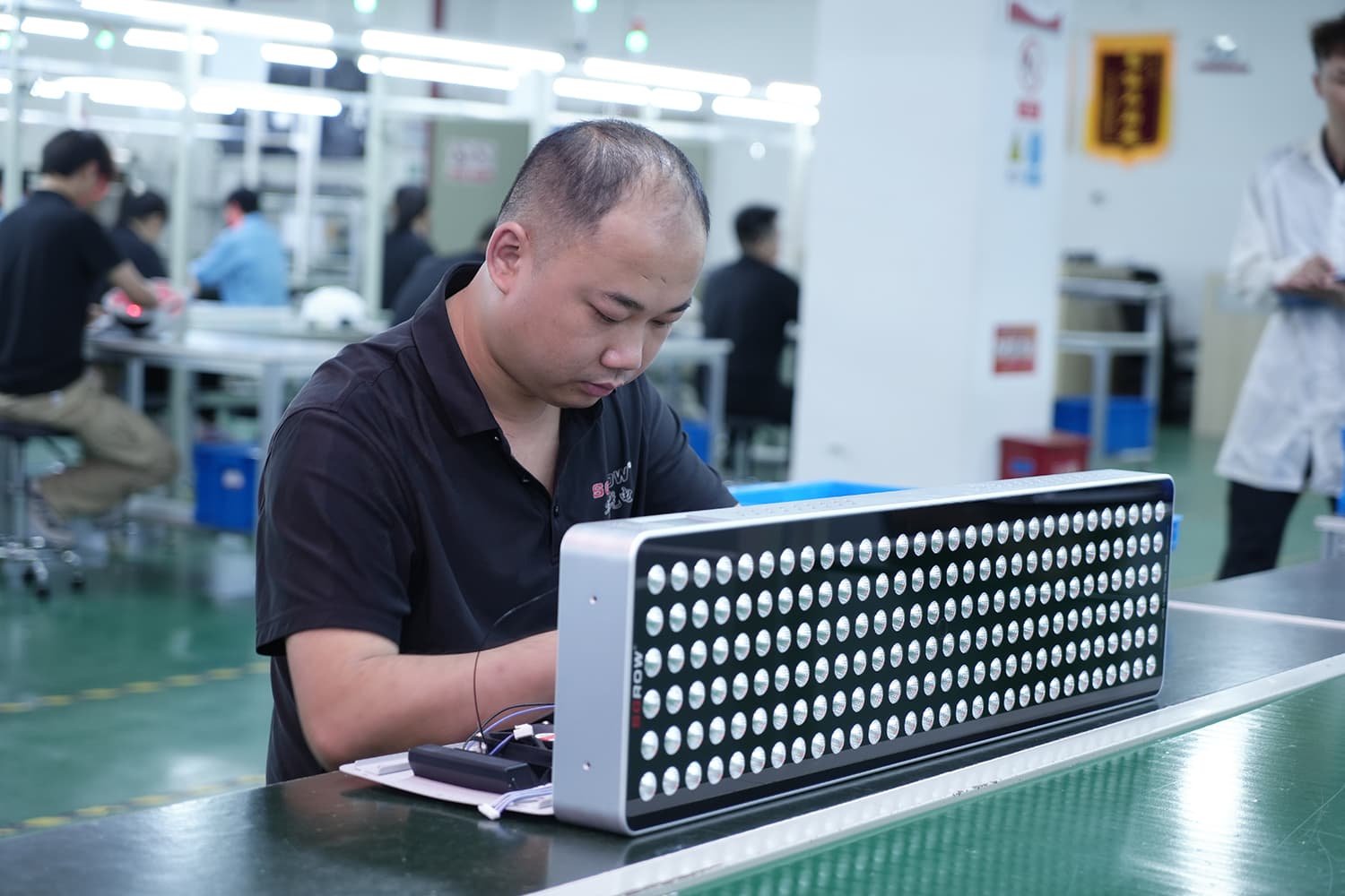 Assembly technician inspecting an LED red light therapy panel during production