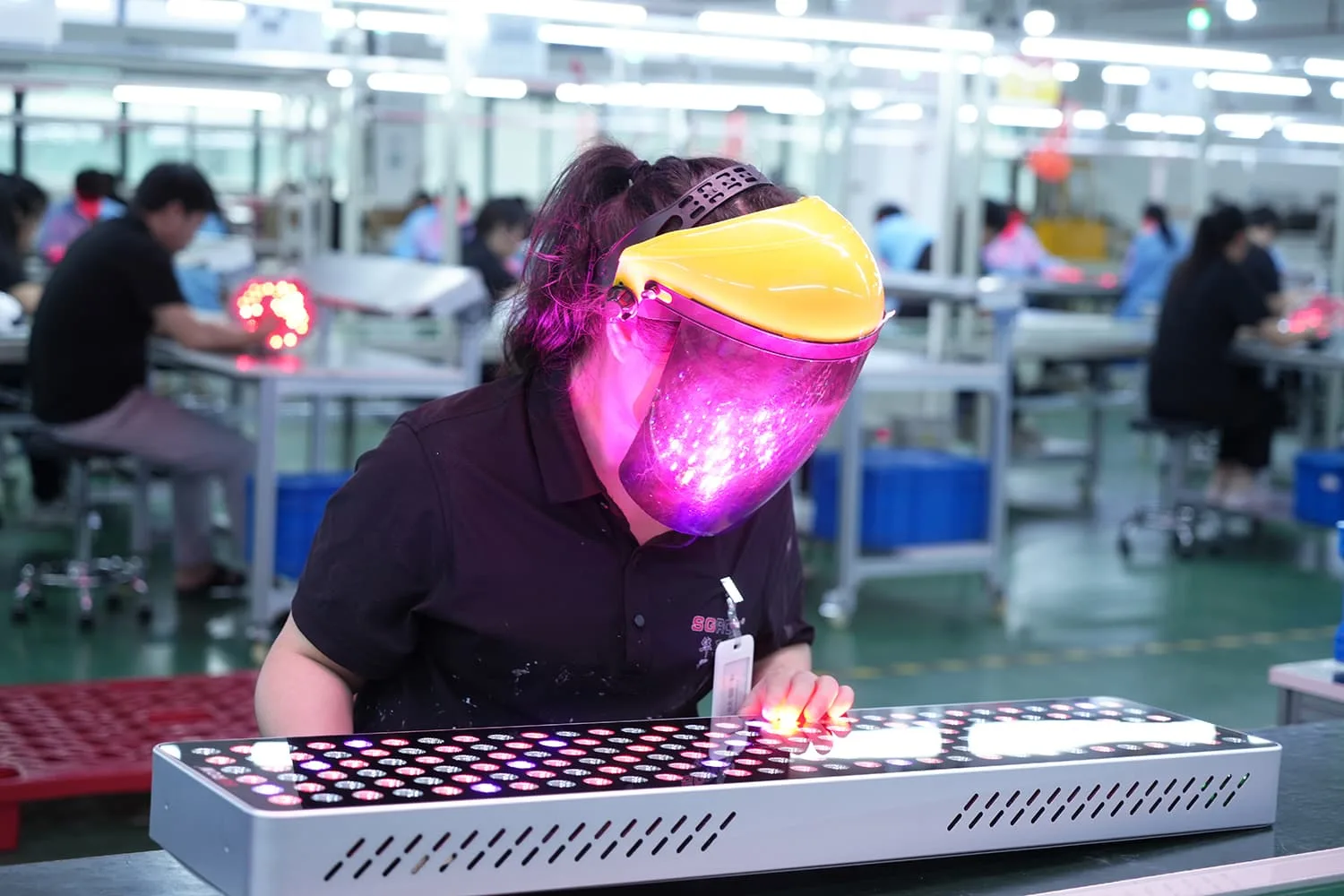 Worker testing red light therapy panel LEDs with protective face shield