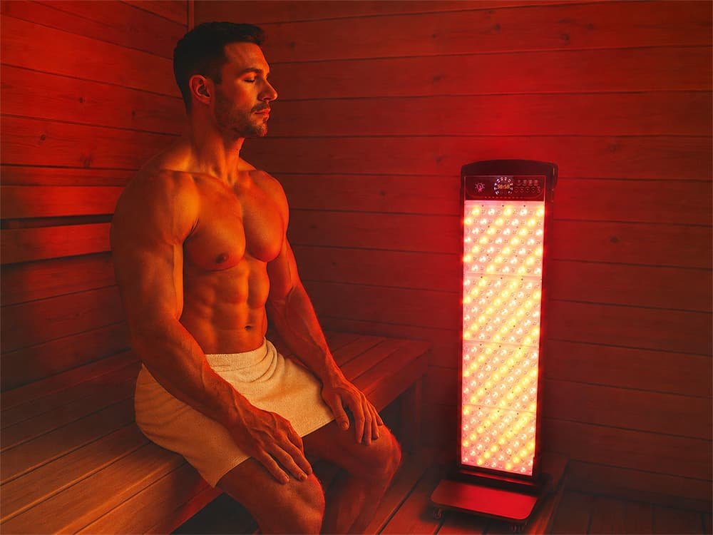 Athletic man seated beside the Wakelife SL280 red light panel in a sauna